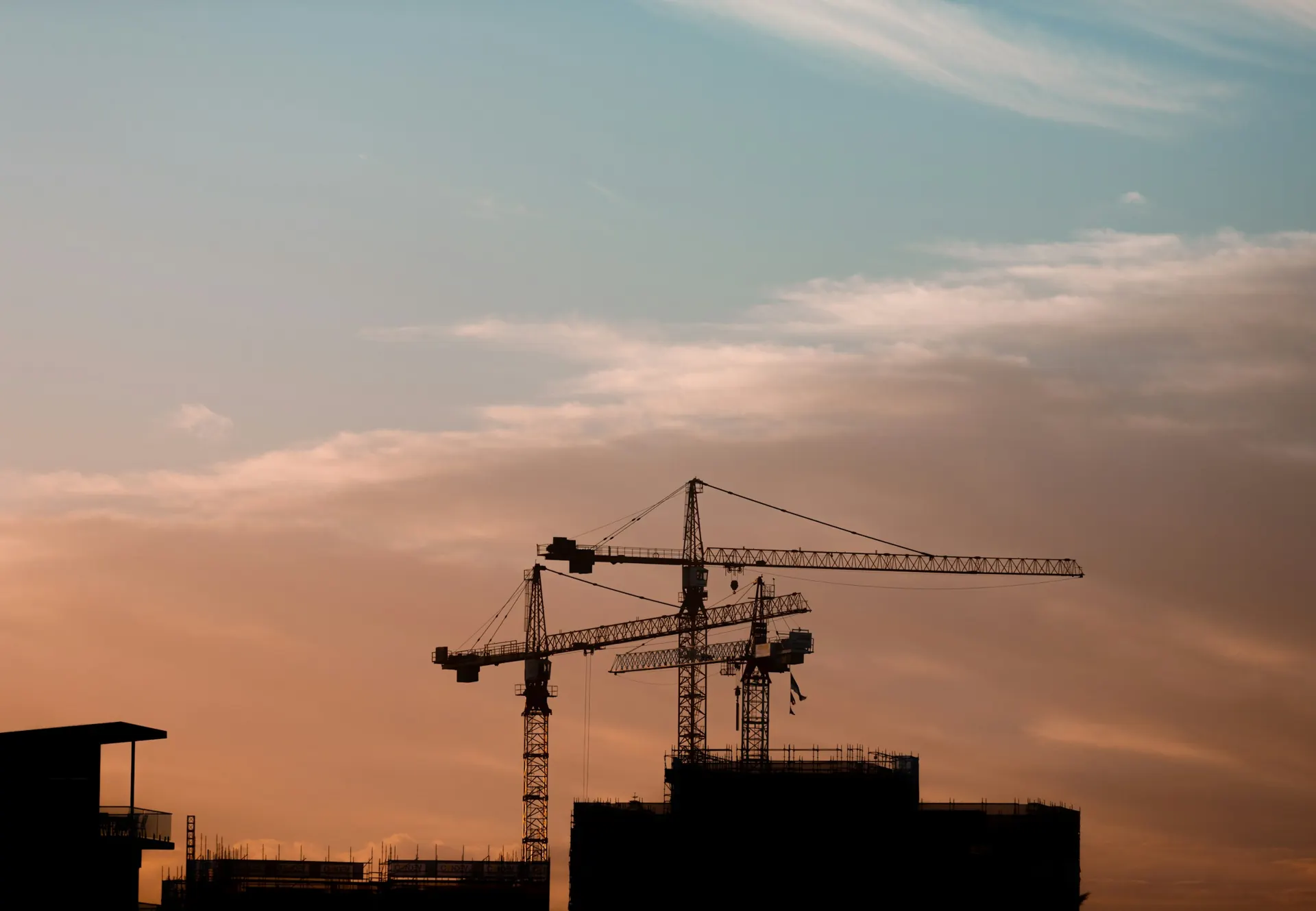 Tower cranes over buildings under construction at dusk