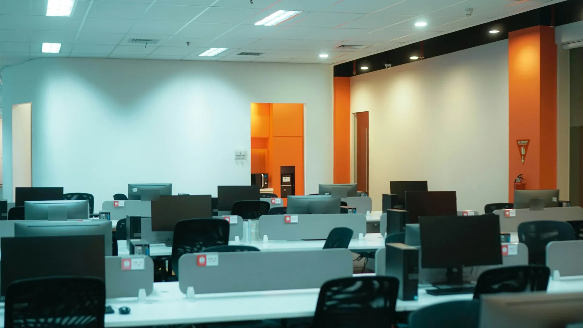 Rows of desktop PCs on desks in an empty office